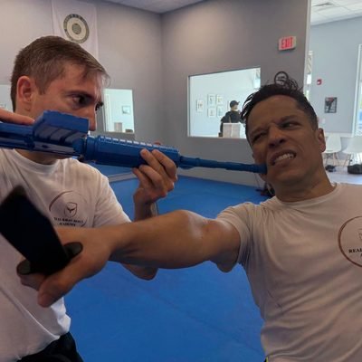 Student practicing a simulated rifle disarm technique at Real Krav Maga Academy.